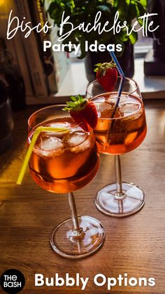 two glasses filled with drinks sitting on top of a wooden table