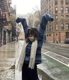 a woman is standing in the rain with her arms up and legs spread wide out