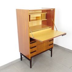 a wooden desk with drawers and a shelf on the top, in front of a white wall