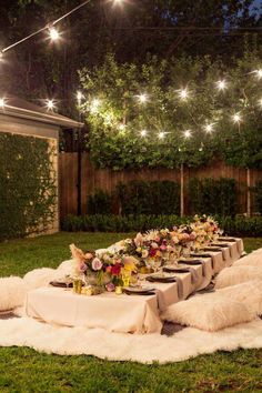 an image of a table with flowers on it and lights strung above the table in the background