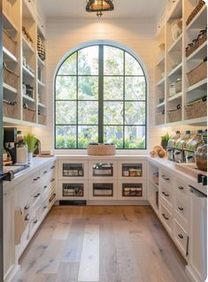 an arched window in a kitchen with white cabinets and wood flooring on the side