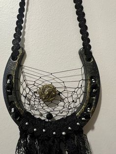 a black and gold necklace hanging from a hook on a wall with beads attached to it