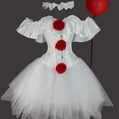 a white dress with red flowers on it and a balloon attached to the waistline