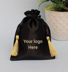 a black bag with gold tassels on it next to a potted plant