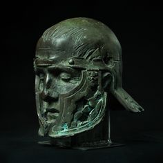 an ancient bronze head sculpture on a black background