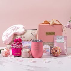 a pink gift box with donuts, flowers and other items in it sitting on a table