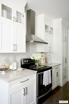 a kitchen with white cabinets and black appliances