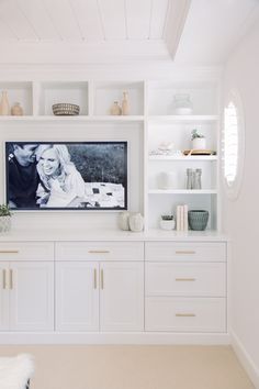 a white entertainment center with built - in shelving and pictures on the wall above it