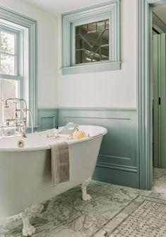 a white bath tub sitting next to a window in a bathroom with blue trim on the walls