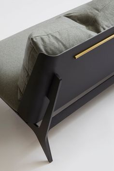 a black bed frame with a green pillow on it