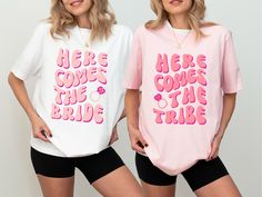 two women standing next to each other wearing t - shirts that say here comes the bride