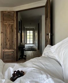 an open door leading into a bedroom with white sheets and pillows