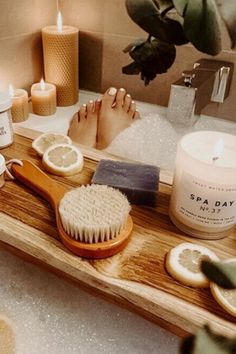 a wooden tray with candles, lemon slices and scrubs on it in a bathroom