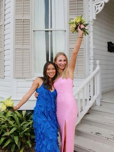 two beautiful women standing next to each other in front of a house