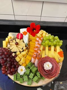 a platter filled with different types of cheeses and grapes on a table top