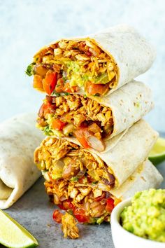 three burritos stacked on top of each other with guacamole