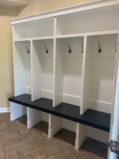 a row of white and black benches with hooks on the wall behind them in a room