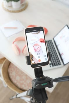 a cell phone sitting on top of a tripod in front of a laptop computer