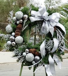 a christmas wreath with silver balls, pineconis and snowflakes on it