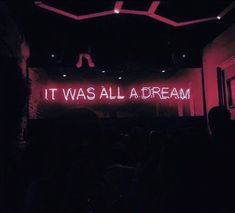 a neon sign that says it was all a dream on the wall in front of an audience