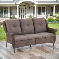 a brown couch sitting on top of a hard wood floor next to a white house