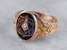 This antique fraternal ring represents the Junior Order of United American Mechanics! The enamel detailing is crisp and bold, and the scrolling designs on the ring's shoulders have a textured relief that feels luxurious. What a great ring! Metal: 10K Yellow and Rose Gold Materials: Black, Red, White, and Blue Enamel Top Measurements: 12 x 15 mm, Oval Ring Size: 11.75 Marks: "OB 10K" Stamped on the inside band Classic Engraved Enamel Jewelry, Classic Enamel Hallmarked Rings, Formal Engraved Enamel Signet Ring, Antique Black Enamel Rings For Collectors, Antique Black Enamel Collectible Rings, Antique Enamel Rings For Collectors, Antique Enamel Rings As Collectibles, Heirloom Engraved Oval Enamel Ring, Heirloom Oval Engraved Enamel Ring