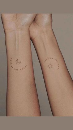 two hands with tattoos on their wrists holding each other's wrists, one has a sun and the other has a crescent moon