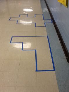 an empty hallway with blue tape on the floor and a yellow sign in the middle