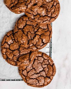 chocolate crinkle cookies on a cooling rack with one cookie broken in the middle