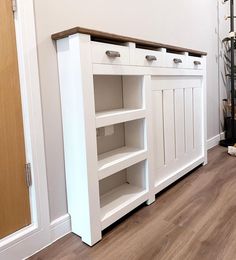 a white cabinet with drawers and shelves on the floor next to a dog laying on the floor