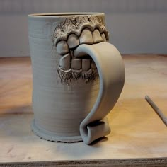 a ceramic mug with teeth on it sitting on a table