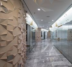 an empty hallway with glass walls and sculptures on the wall, along with large mirrors