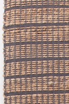 an area rug with brown and tan woven squares on the bottom, in front of a white wall