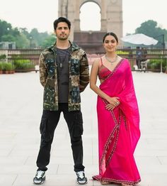 a man and woman standing next to each other in front of an arch of triumph