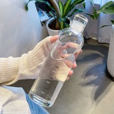 a person is holding a water bottle in their left hand while sitting on a couch