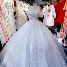 a white wedding dress is on display in a store with lots of dresses hanging up