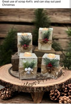 four wrapped presents sitting on top of a wooden table next to pine cones and candles