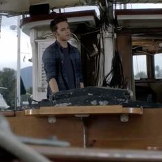 a man standing on the deck of a boat looking at something in the water behind him