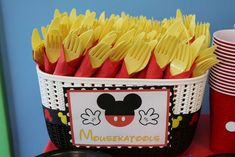 a mickey mouse themed birthday party with paper plates and forks in a basket on the table