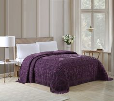 a bed with a purple comforter and white pillows