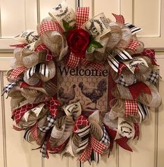 a welcome wreath is hanging on the front door with red and white ribbon around it