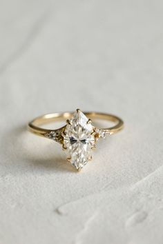 a gold ring with an oval cut diamond in the center and three smaller round diamonds on each side