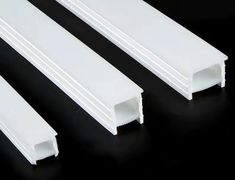 three white plastic tubes sitting next to each other on a black surface with one end open