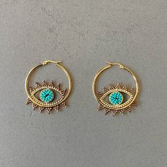 Evileye protection hoop earrings beads hoop earrings Miyuki earrings Miyuki bead earrings evil eye shape earrings bohemian earrings everyday Add a unique style to any look with these bohemian style earrings featuring an evil eye. Constructed with Miyuki seed beads in a combination of aqua and gold seed beads, they are sure to catch any eye with their stunning design. Lightweight and comfortable. Item Details *Material: Stainless Steel *Stone: Glass seed beads *Earring size: 1.57in (4cm) *Weight: Summer Evil Eye Jewelry With Round Beads, Bohemian Evil Eye Earrings As Gift, Bohemian Evil Eye Dangle Jewelry, Trendy Handmade Festival Hoop Earrings, Trendy Evil Eye Jewelry For Festivals, Evil Eye Hoop Earrings As A Gift, Evil Eye Hoop Earrings Gift, Evil Eye Dangle Hoop Earrings As Gift, Dangle Hoop Earrings With Evil Eye As Gift