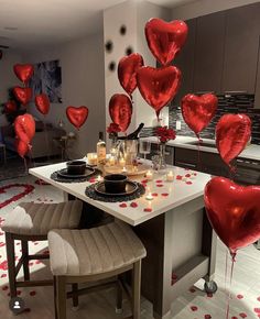 red balloons are floating in the air over a table with candles and plates on it