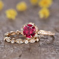 a close up of a ring with a red stone in it on a wooden surface