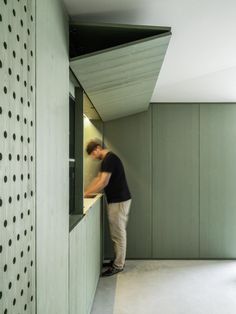 a man standing in the corner of a room looking at something on the wall behind him