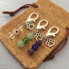 three charms are sitting on top of a woven piece of cloth next to a bag