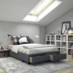 a bedroom with a bed, bookshelf and skylight in the ceiling above it