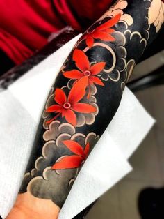 a woman's arm with red flowers on black and grey ink in the middle